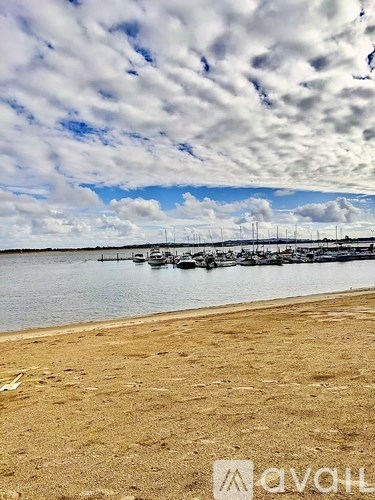 A beach with boats in the water and a cloudy sky.