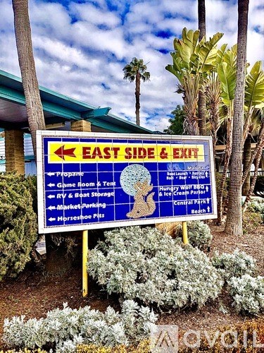A blue sign with white text is pointing to the east side and exit of a place.