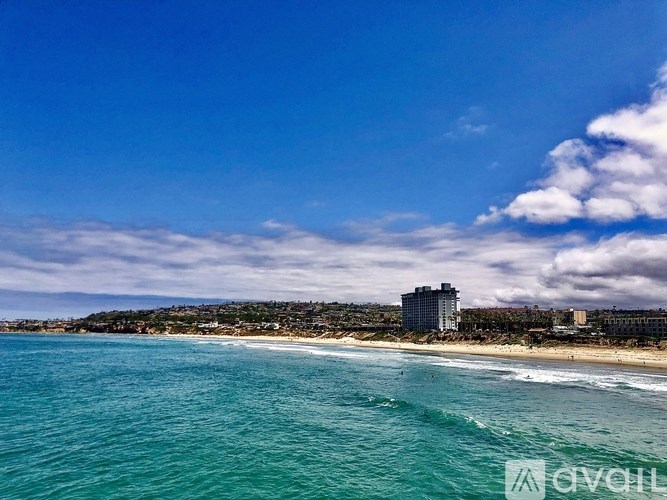 A beach with a building in the background and the sky is blue.
