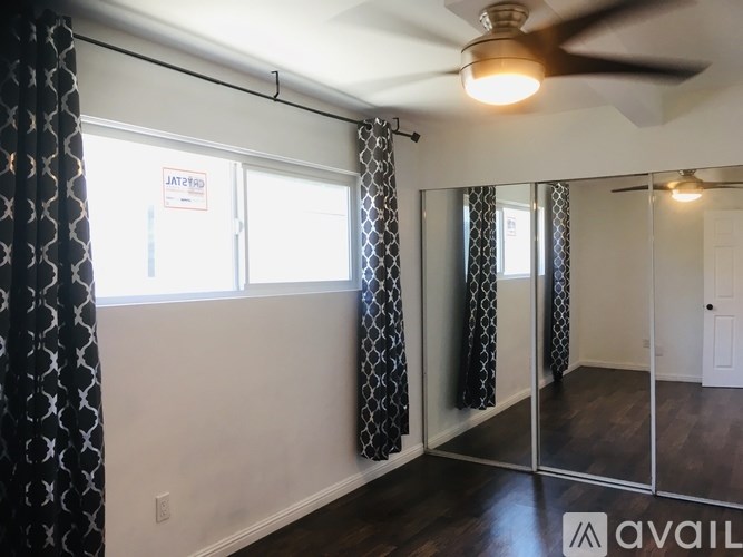 A room with a ceiling fan and a mirrored wall.