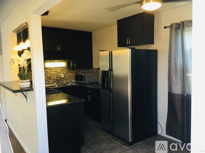 A kitchen with black cabinets and a black refrigerator.
