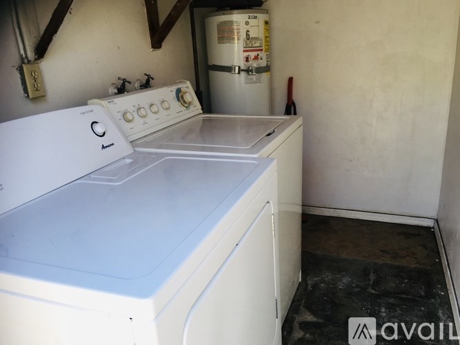 A white dishwasher is in a small room with a washing machine behind it.