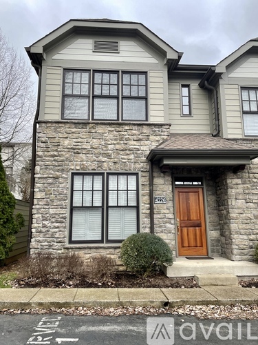 A two-story house with a brown door and a stone wall.