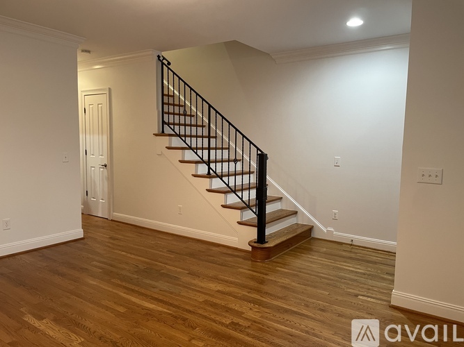 A wooden staircase with a black railing leads up to a door.