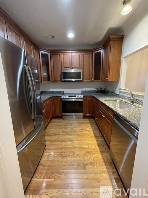 A kitchen with wooden cabinets and a stainless steel refrigerator.