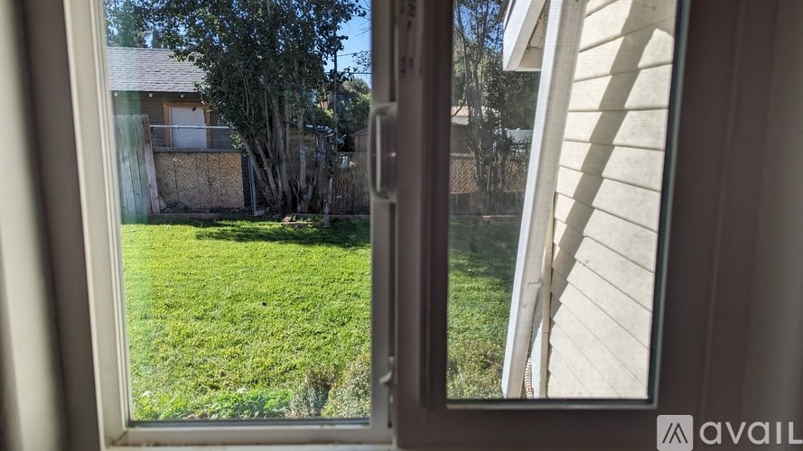A window with a view of a green lawn and a house.