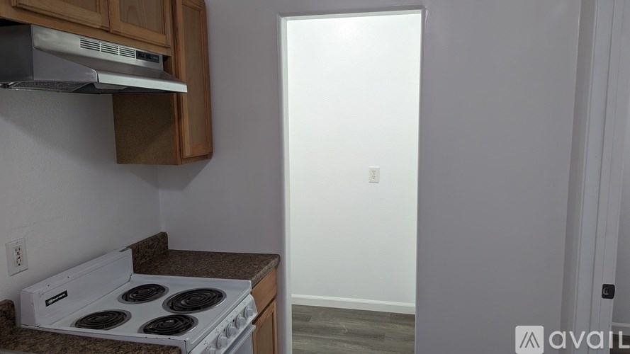 A white stove is in a kitchen with a white wall and a white door.