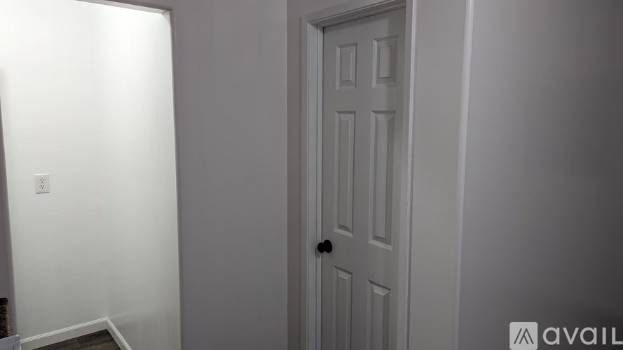 A white door is in a room with a white wall and a light switch.