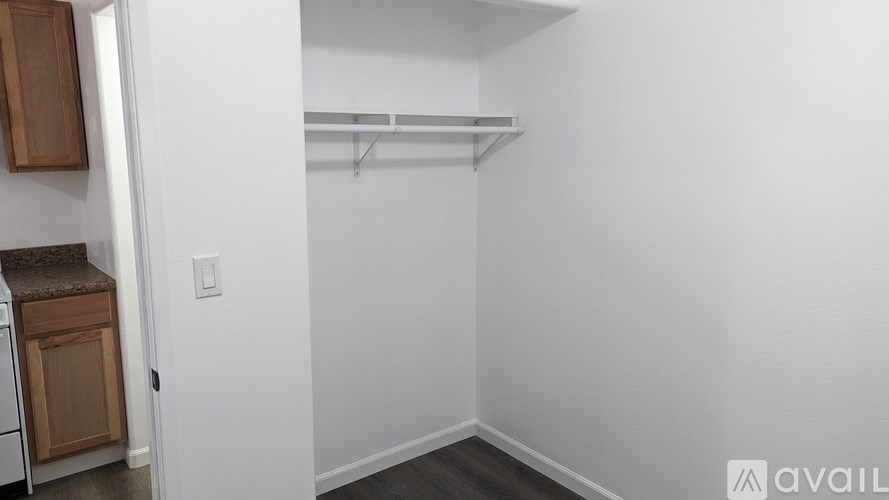 A white wall with a shelf and a cabinet.
