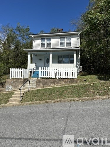 A white house with a blue door and a white picket fence.
