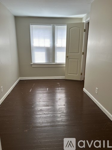A room with a wooden floor and a window with blinds.