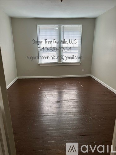 A room with wooden flooring and a window with blinds.