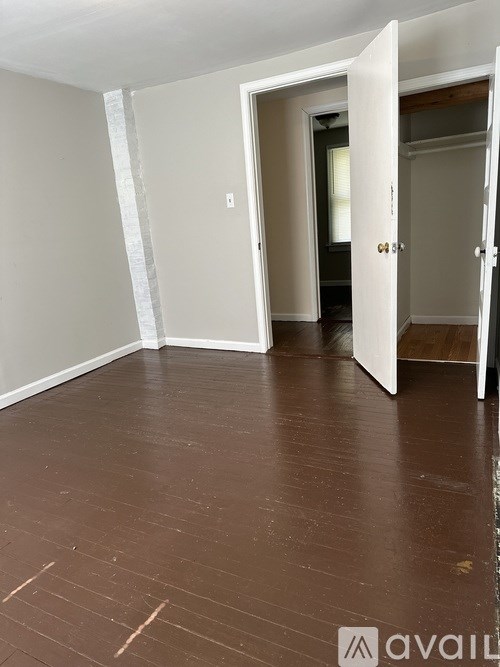 A room with wooden flooring and two doors, one of which is open.