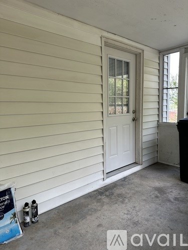 A room with a white door and a window with a view of trees outside.