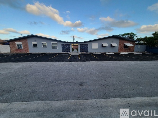 A parking lot with a building in the background and a sign that says "AVAIL".