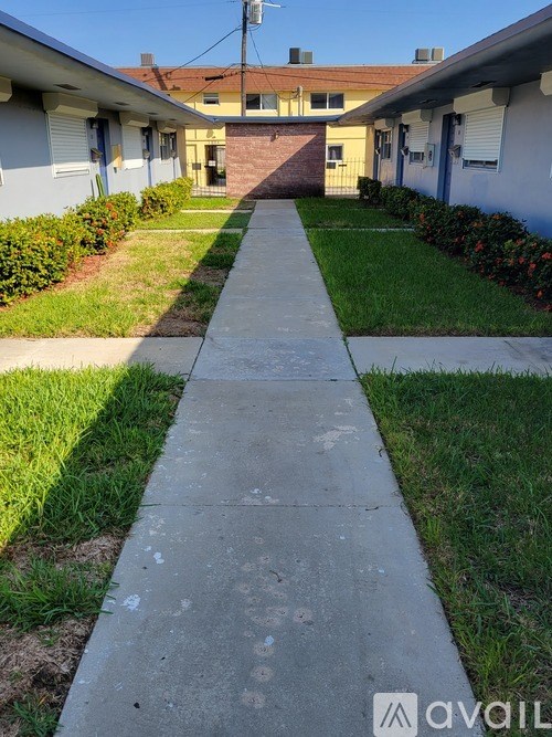 A long concrete walkway separates two rows of houses.