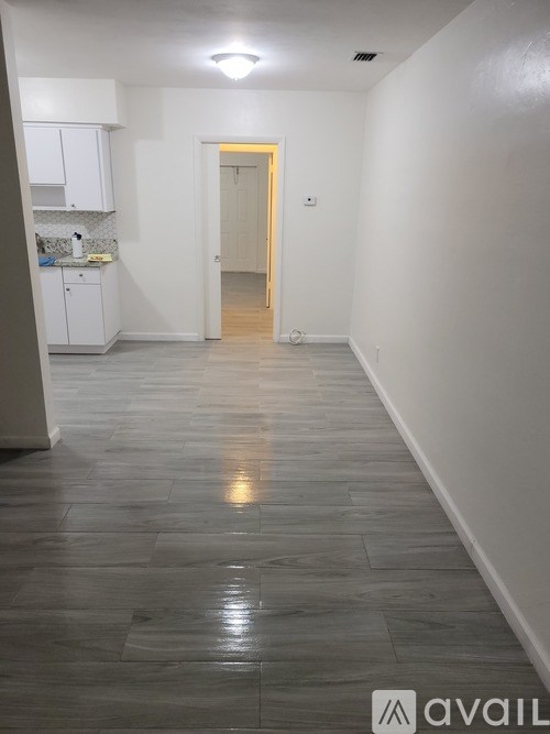 A hallway with a tiled floor and a door at the end.