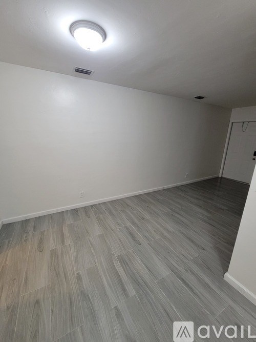 A room with a light on the ceiling and a wooden floor.