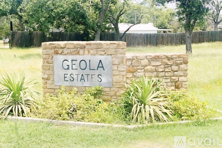 A sign that says Geola Estates in front of a fence.