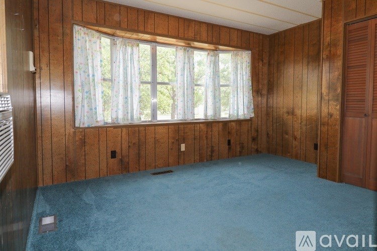 A room with wooden walls and a window with curtains.