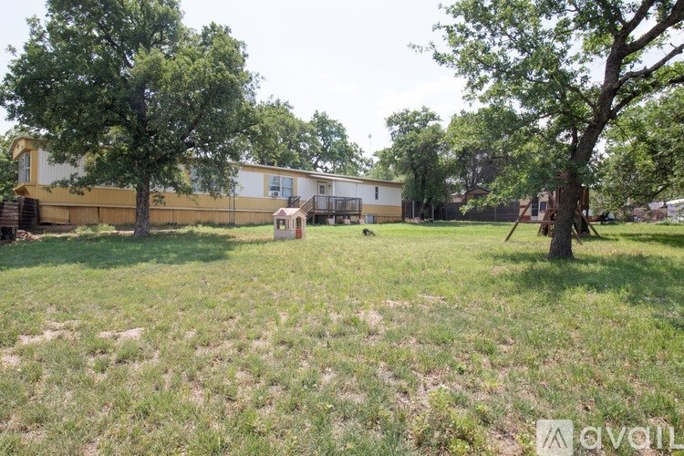 A grassy area with trees and a building in the background.
