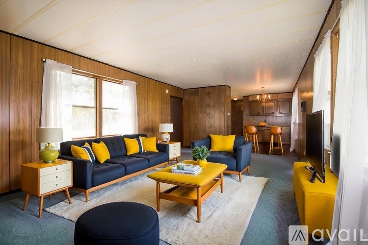 A living room with a blue couch, yellow accents, and a wooden coffee table.