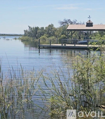 A calm lake with a dock and a gazebo in the distance.