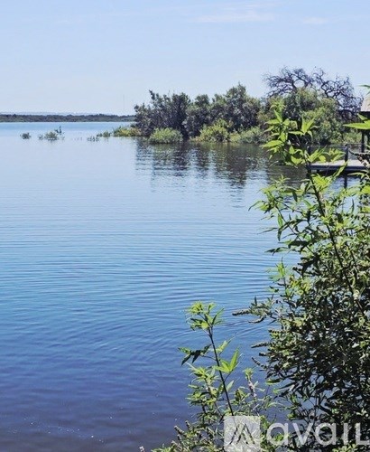 A serene lake surrounded by greenery under a clear sky.