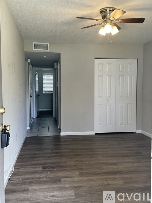 A hallway with a fan and a door at the end.