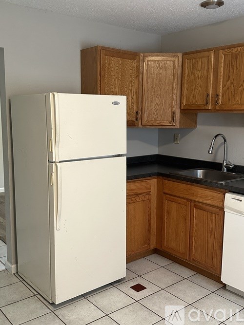 A white fridge in a kitchen with wooden cabinets.