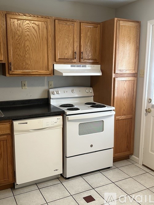 A kitchen with wooden cabinets and white appliances.