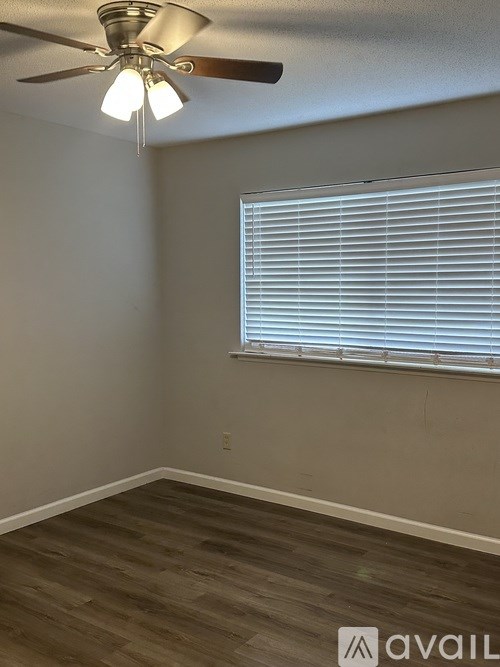 A room with a ceiling fan and a window with blinds.