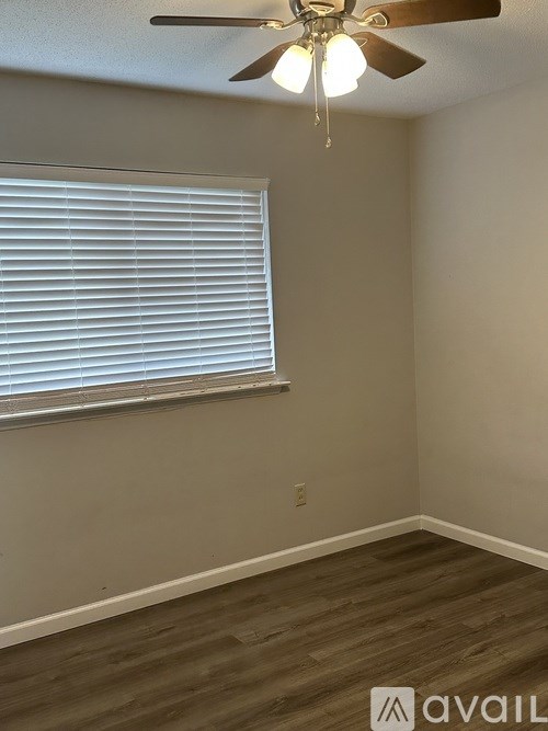 A room with a ceiling fan and a window with blinds.
