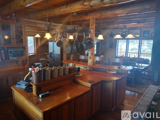 A kitchen with wooden cabinets and a large island with a countertop and a pot rack.