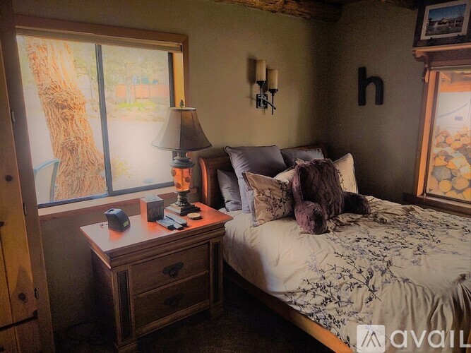 A bedroom with a bed, nightstand, and window.
