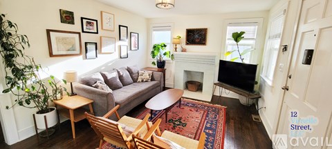 A living room with a grey couch and a fireplace.