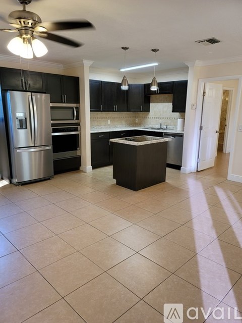 A kitchen with black cabinets and a silver refrigerator.