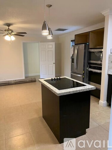 A kitchen with a black island and a white door in the background.