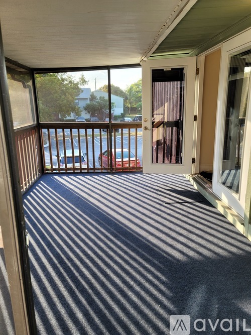 A balcony with a striped carpet and a view of the street.