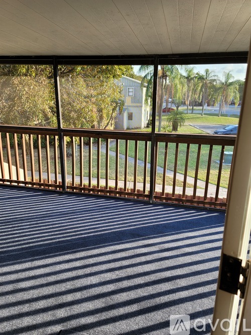 A balcony with a metal railing and a view of a street and trees.