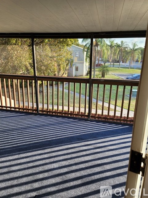 A balcony with a metal railing and a view of a street and trees.