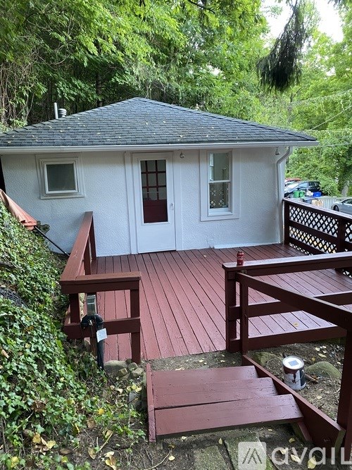 A small white house with a red deck and a wooden bench.