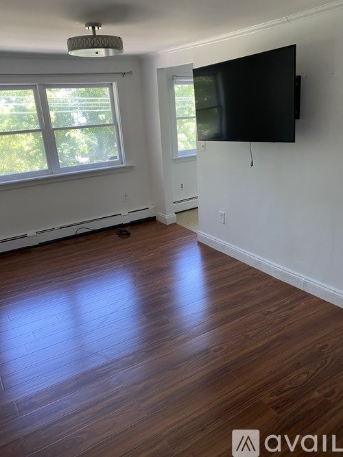 A room with a flat screen TV mounted on the wall and a window with blinds.