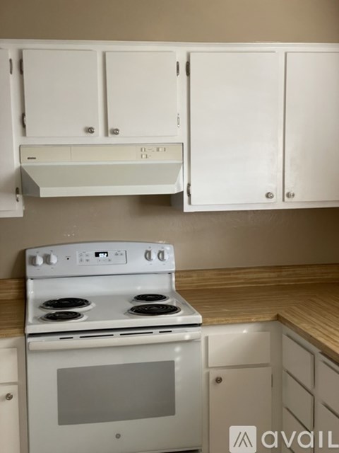 A white oven with a stove top sits under a cabinet.