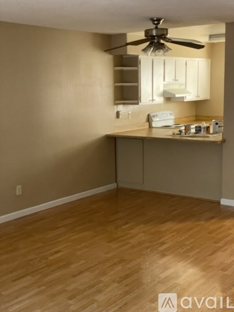 A kitchen area with a fan and wooden flooring.