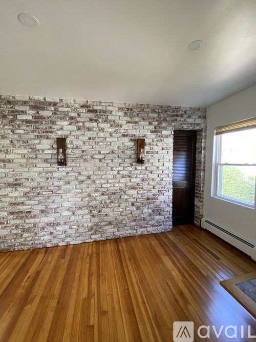 A room with a brick wall and wooden flooring.