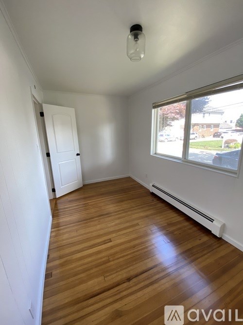 A room with wooden floors and a window overlooking a street.