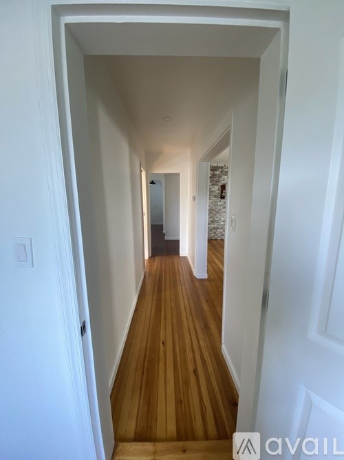 A long hallway with wood floors and white walls.