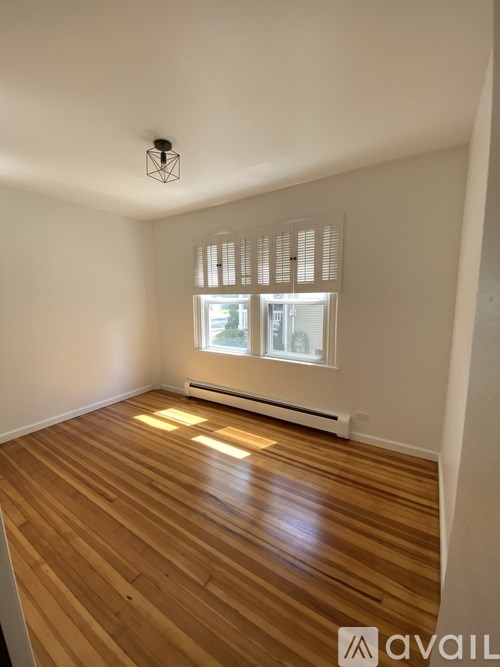 A room with wooden flooring and a window with blinds.