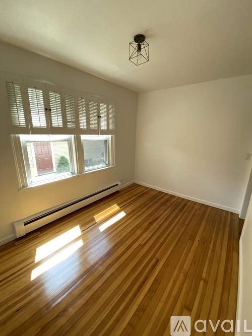 A room with wooden flooring and a window with blinds.
